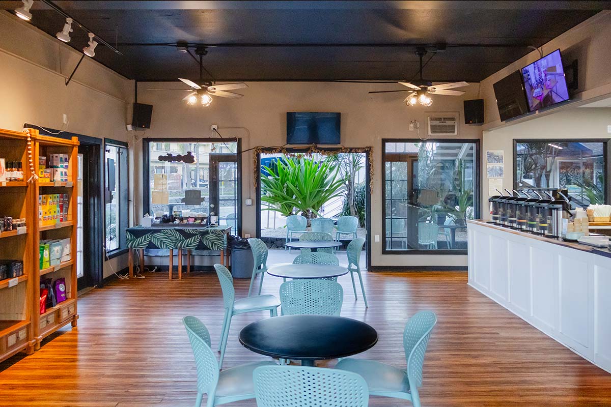 Kaʻū Coffee Roasters Cafe interior with tables, chairs, and a sampling counter.