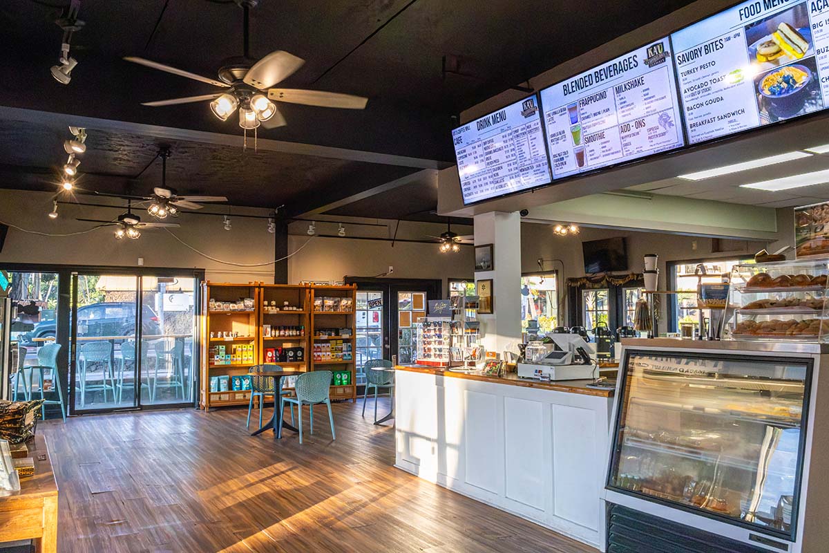 Interior of Kaʻū Coffee Roasters Cafe with seating area, counter, and display cases.